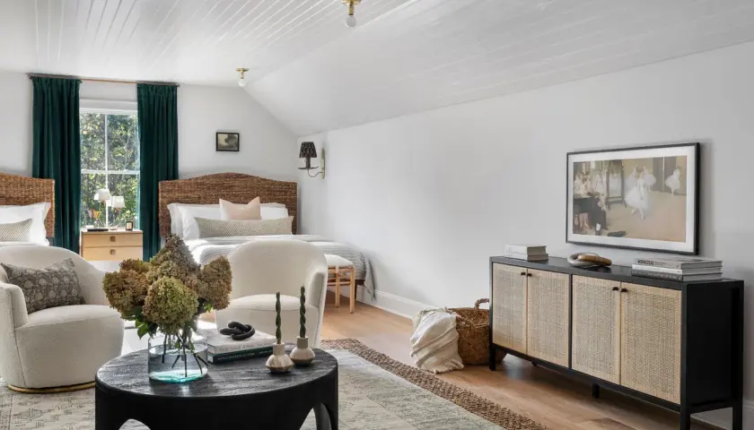 A cozy bedroom with a mix of dark and light wood furniture, featuring rattan headboards, a dark wood cabinet, and light wood nightstands.