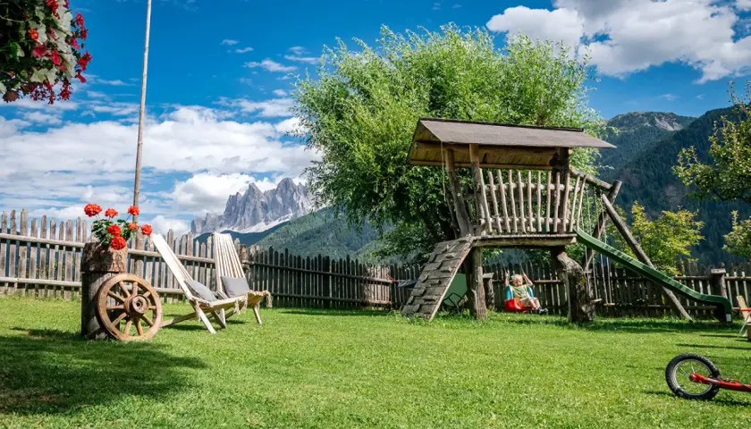 Giardino con altalena e montagne sullo sfondo, ideale per agriturismi con gallo rosso.