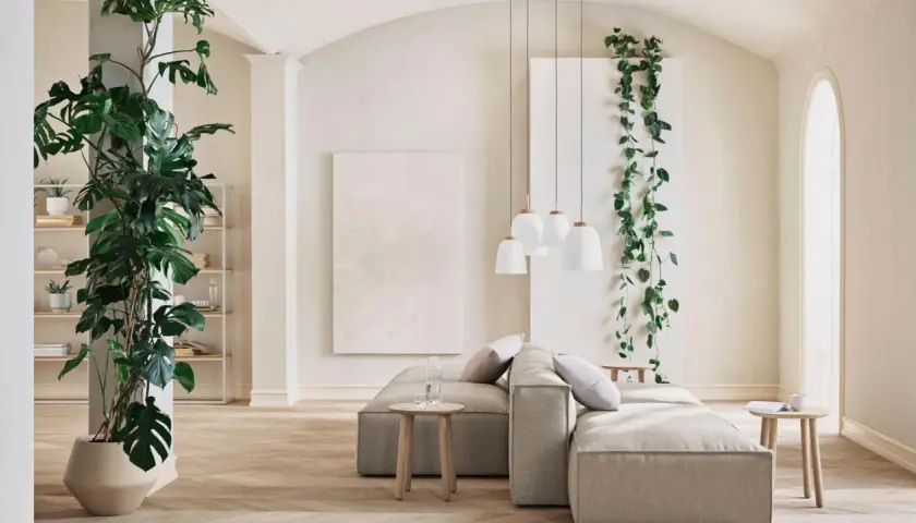 Ein großes, rankendes Zimmerpflanzen-Ensemble umrahmt eine gemütliche Wohnzimmerecke mit einem beigen Sofa und Hängeleuchten.