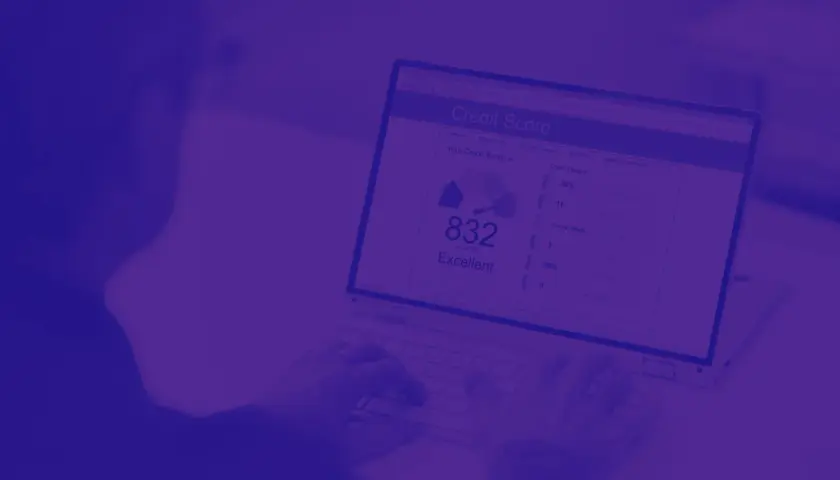 Osoba pisząca na laptopie, na ekranie którego widnieje raport oceny kredytowej z wynikiem 832.