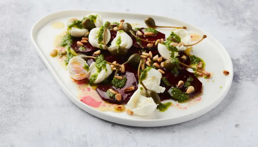 Salade de betterave fumée, mozzarella, pignons et câpres, arrosée d'une sauce verte.