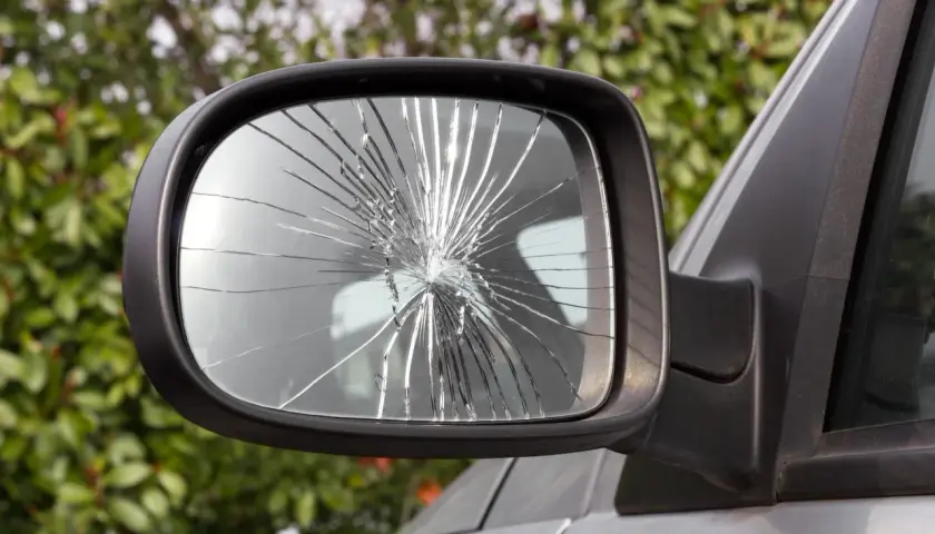 Specchietto rotto dell'auto, con il vetro frantumato in mille schegge che riflettono la luce.