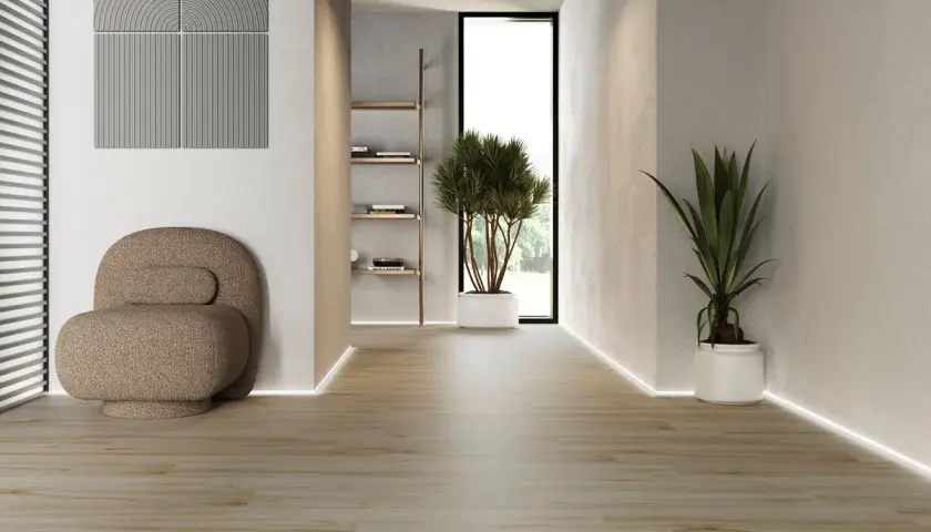 Ljus hall med träliknande klinkers på golvet, en bekväm fåtölj och gröna växter.