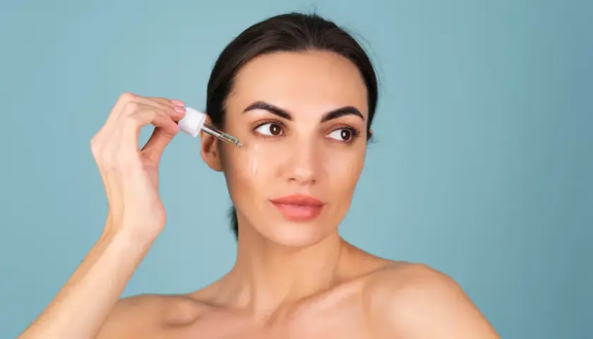 Kvinnan applicerar serum med retinol ansikte.