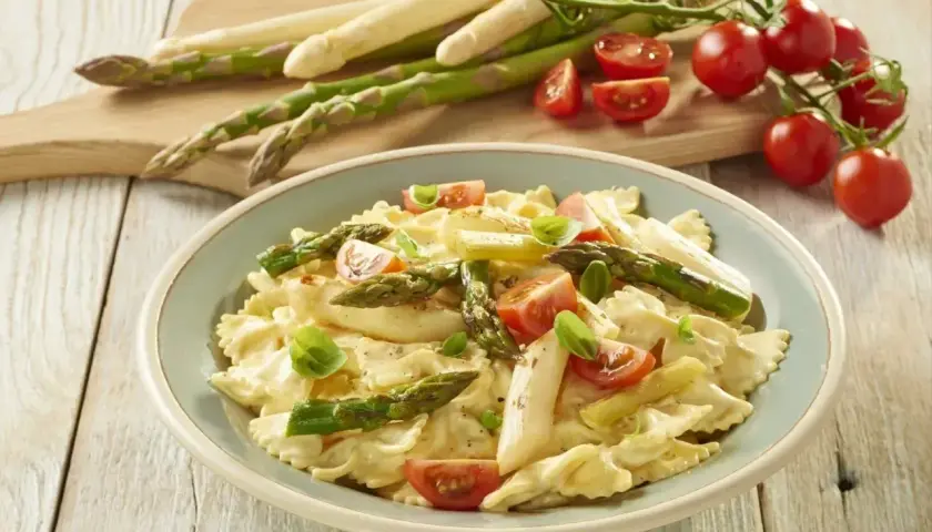 Pyszne szparagi na obiad w kremowym sosie z makaronem farfalle, pomidorkami i bazylią.