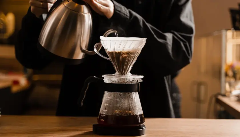 Person gießt heißes Wasser über Kaffeepulver in einem Filter. Die richtige filterkaffee temperatur ist entscheidend für den Geschmack.