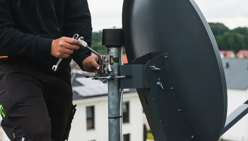 Technik reguluje antenę satelitarną, by jak najlepiej ustawić sygnał.