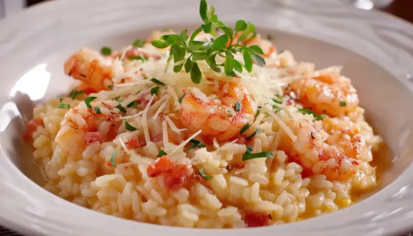 Un crémeux risotto au gambas, garni de parmesan râpé et d'une touche de verdure fraîche. Un délice pour les yeux et les papilles.