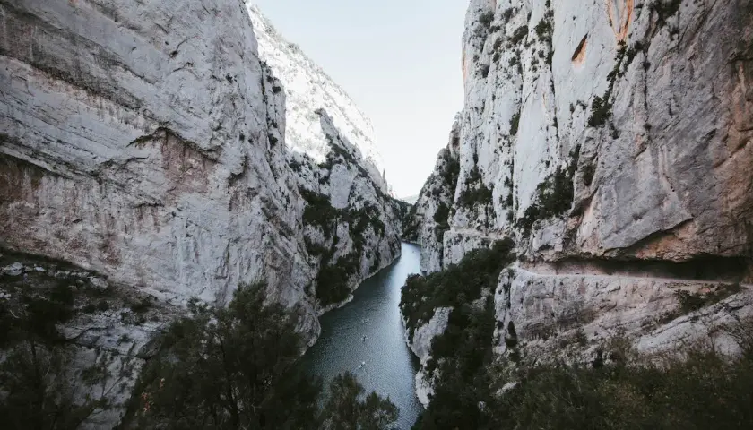 El río serpentea entre imponentes paredes rocosas en el congost de Montrebei. Pequeñas embarcaciones navegan tranquilamente por sus aguas.