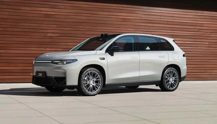 Elegante auto elettrica Leapmotor C10 color argento metallizzato, con un design moderno e linee aerodinamiche, parcheggiata davanti a una parete di legno.