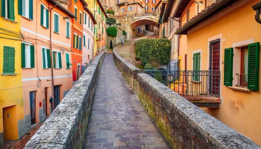 Un vicolo pittoresco a Perugia, con case colorate e un ponte in pietra. Perfetto per scoprire le cose da fare a Perugia.