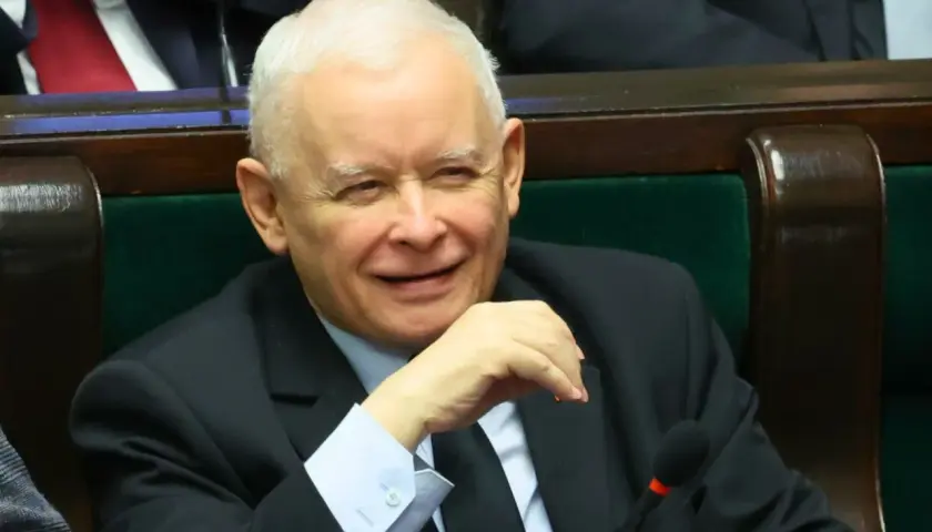 Jarosław Kaczyński w garniturze, siedzi w fotelu, uśmiecha się.