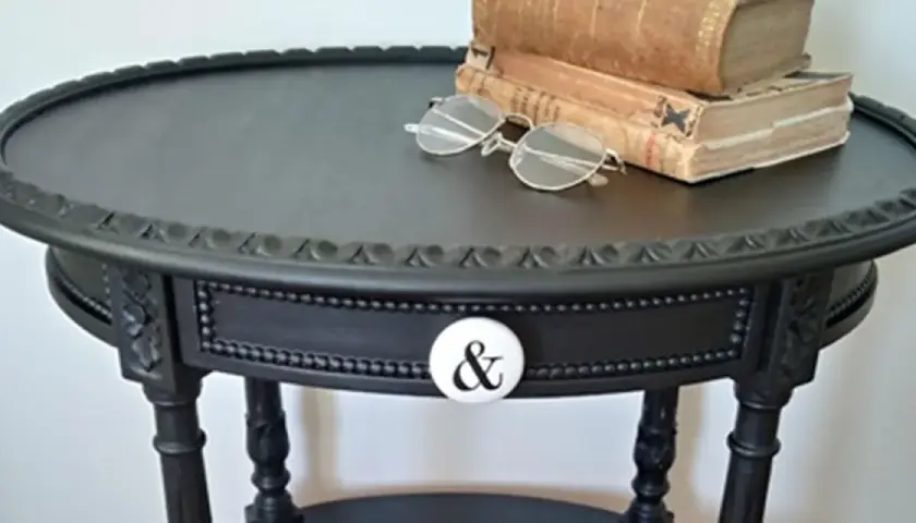 Come trasformare un vecchio comodino in un pezzo d'arredo chic: un tavolino nero con pomello a "&" e libri antichi.