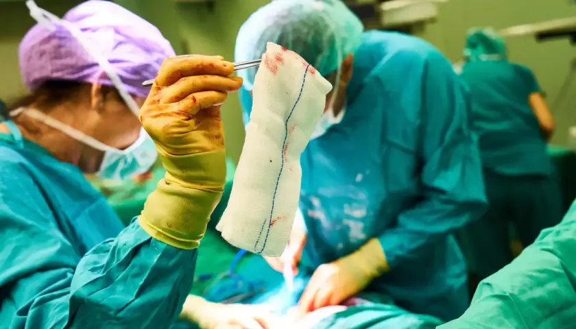 Chirurghi in sala operatoria. La mano guantata tiene una garza insanguinata, un dettaglio che potrebbe far pensare alle tabelle risarcimento malasanità morte.