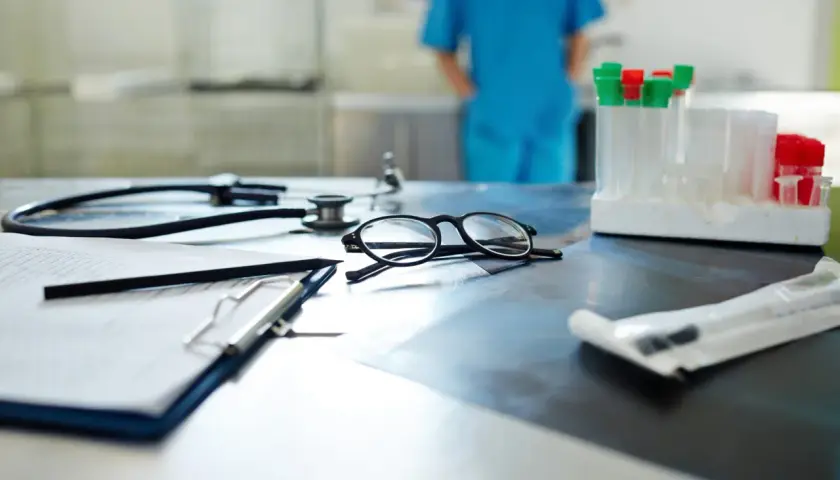 Occhiali, stetoscopio e provette su un tavolo. Il medico di base quanti pazienti ha oggi?