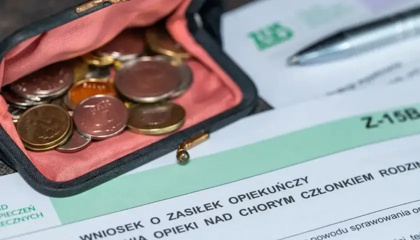 Portmonetka z monetami obok wniosku o zasiłek opiekuńczy.