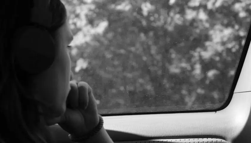 Ragazza con cuffie guarda fuori dal finestrino, persa nei suoi pensieri, come in un loop di depressione, ripetere sempre le stesse cose.