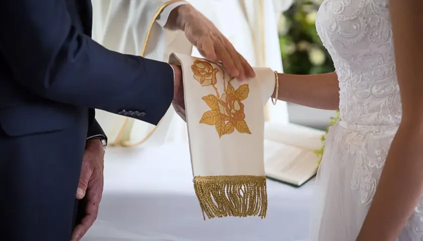 Dłoń księdza błogosławi parę podczas ceremonii, symbolizując przygotowanie do małżeństwa.