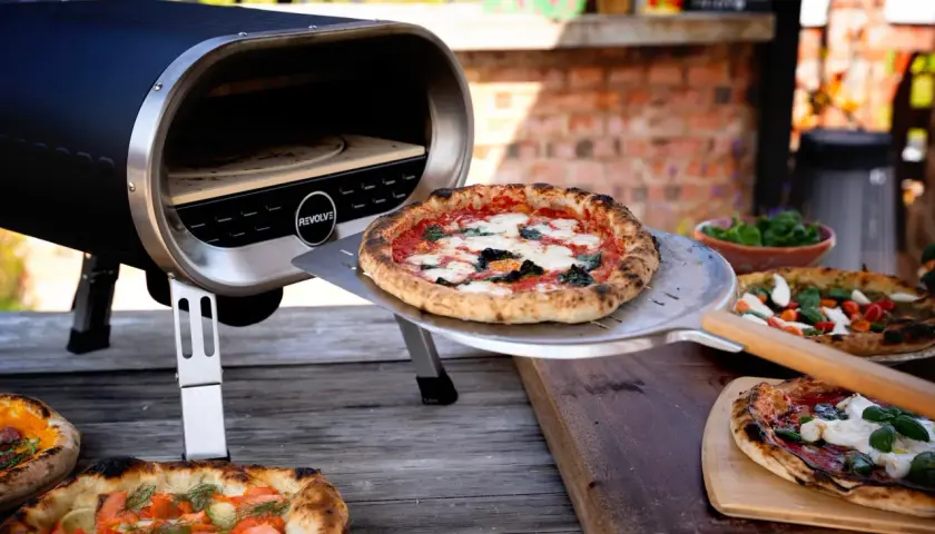 Piec do pizzy z otwartą komorą, na stole leżą świeżo upieczone pizze.