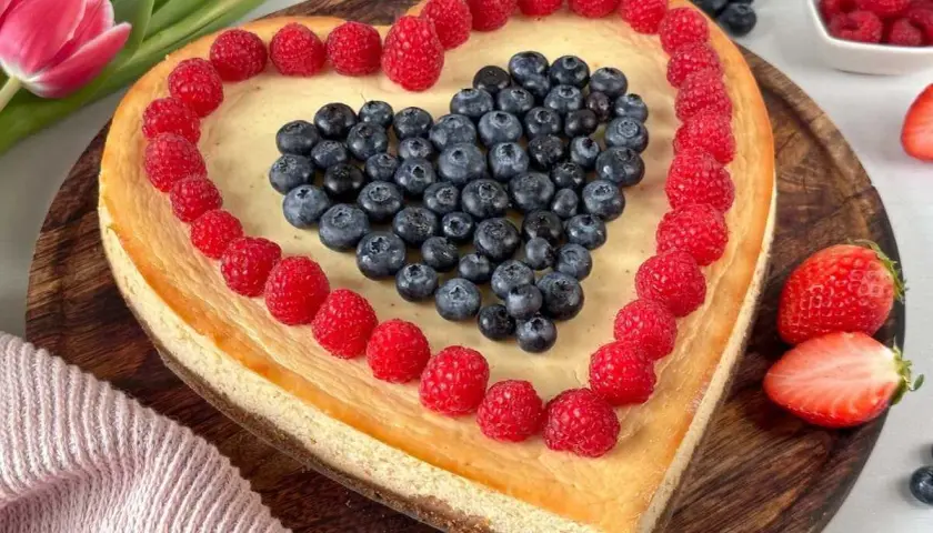 Herzförmiger Kuchen zum Muttertag, dekoriert mit Himbeeren und Blaubeeren. Ein süßes Dankeschön für Mama.