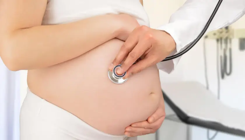 Medico ascolta battito fetale su pancia di donna incinta, controllo per gestosi gravidica.