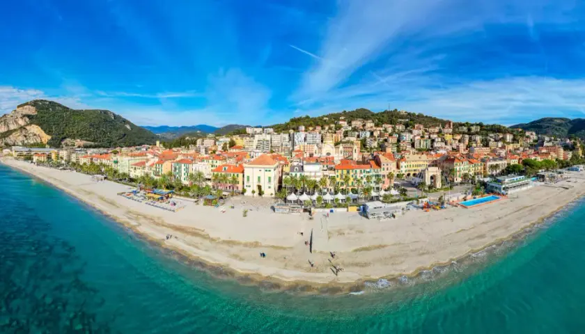Vue panoramique de la plage et de la ville colorée de Finale Ligure, Italie, sous un ciel bleu éclatant.