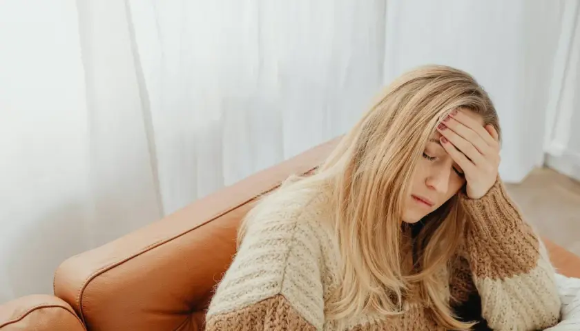 Donna bionda con la mano sulla fronte, forse per un mal di testa. Si chiede a cosa serve il Depakin per alleviare il dolore.
