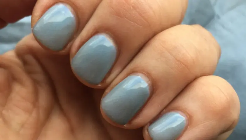 En hand med ljusblå, glansig inglot nagellack.