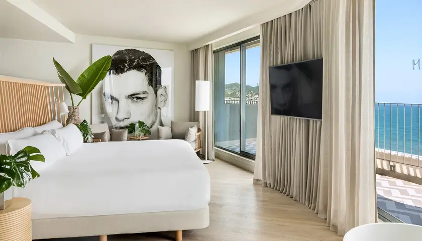 Habitación moderna en el hotel Terramar Sitges con cama king, arte de gran tamaño y vistas al mar.