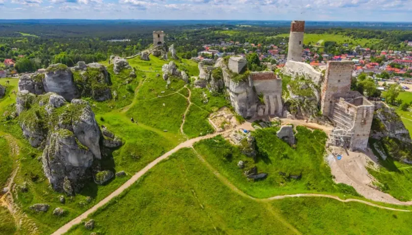 Ruiny zamków na wapiennych skałach, malowniczy szlak Orlich Gniazd. Zielone wzgórza i błękitne niebo.