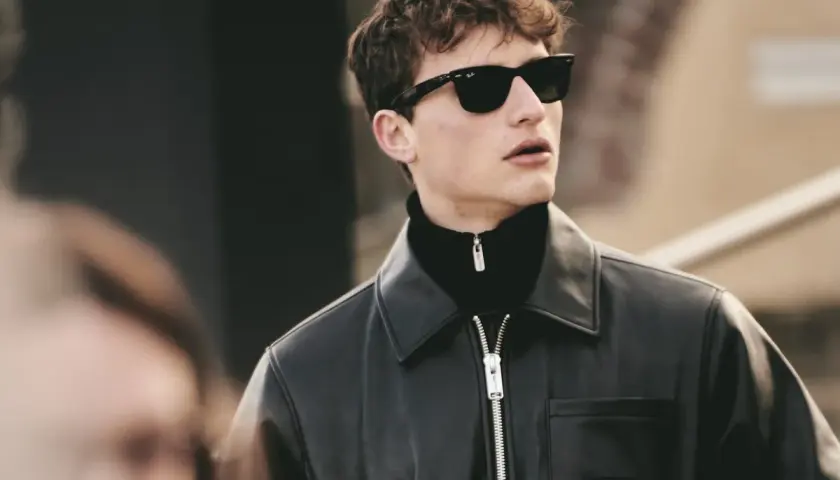 Joven con gafas de sol y chaqueta de cuero, luciendo modernos cortes de pelo hombre joven.