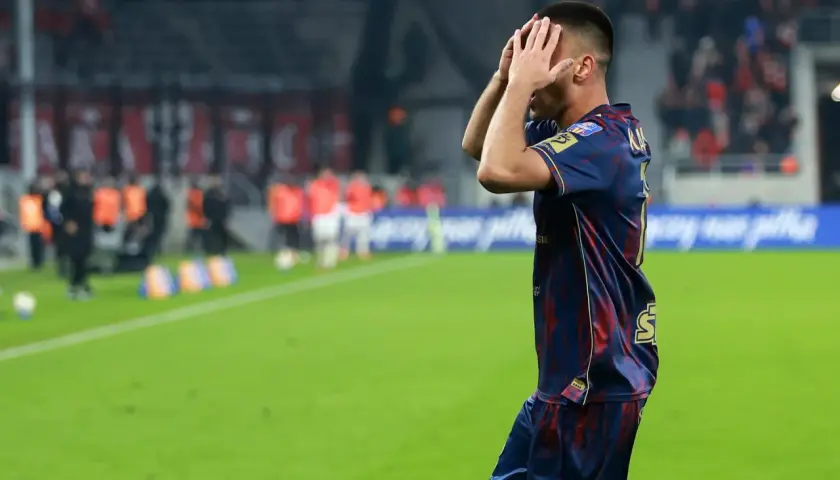 Piłkarz Pogoń Szczecin z rękami na głowie, w tle mecz z Widzewem Łódź.