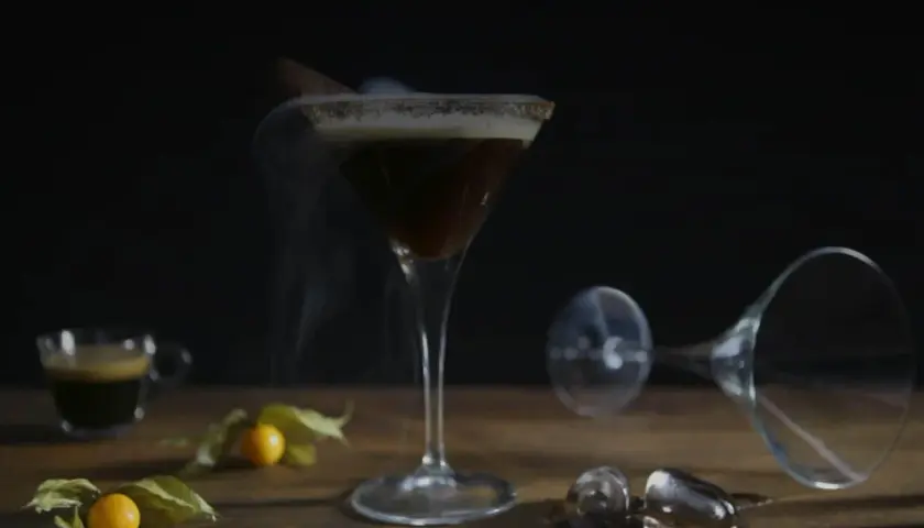 Ein dampfender Espresso Martini mit Zimt und einer kleinen Espressotasse daneben.