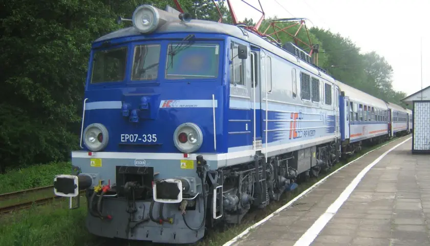 Niebieska lokomotywa EP07-335 PKP Intercity z pociągiem pasażerskim na stacji.