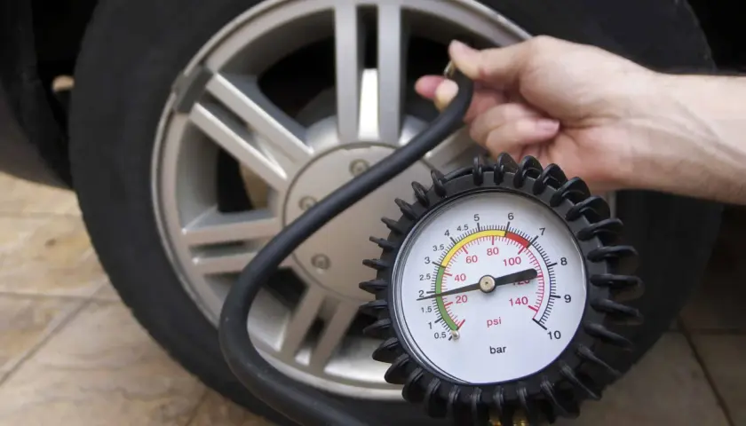 Manometro collegato a una ruota d'auto, dove è scritta la pressione dei pneumatici.