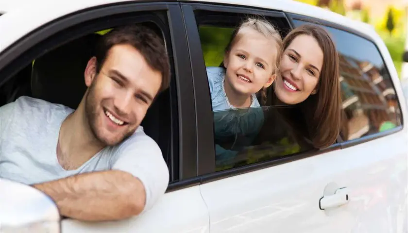 Famiglia sorridente in auto. Pensano al passaggio di proprietà tra familiari costo per un nuovo veicolo.
