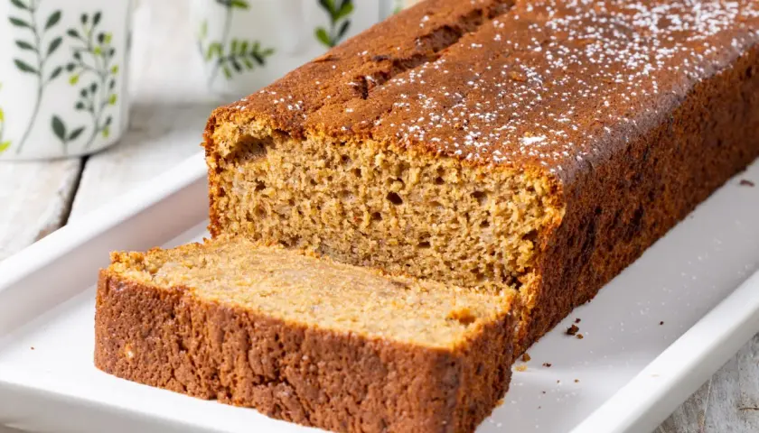 Fetta di banana bread light, soffice e dorata, cosparsa di zucchero a velo. Perfetta per una colazione sana.