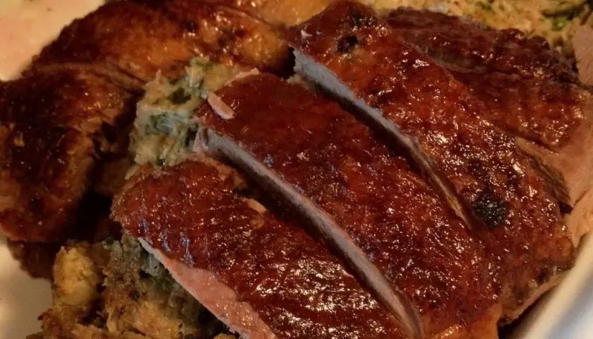 Gęś Ania gotuje. Pyszna, pieczona gęś z chrupiącą skórką i aromatycznym farszem, pokrojona na kawałki.