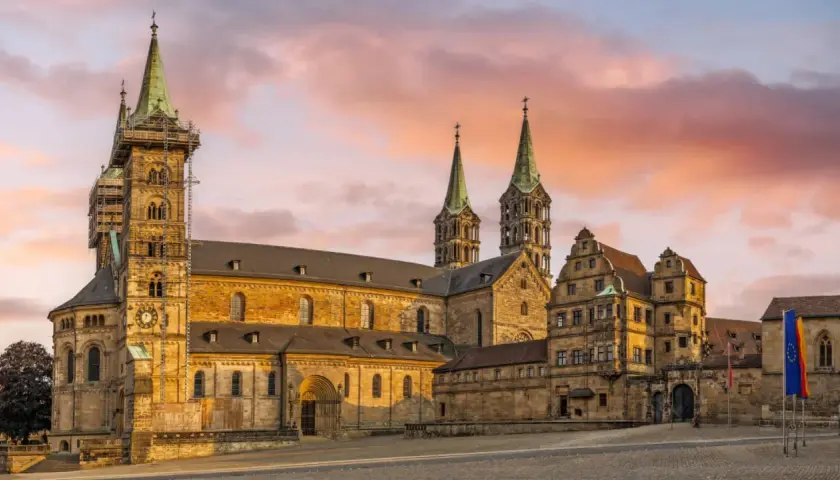 Bamberg Altstadt: Majestätischer Kaiserdom mit Türmen im Abendlicht, umgeben von historischen Gebäuden.