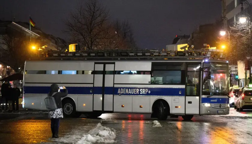 Ein Bus mit der Aufschrift "ADENAUER SRP+" steht im Dunkeln. Eine Person fotografiert ihn.