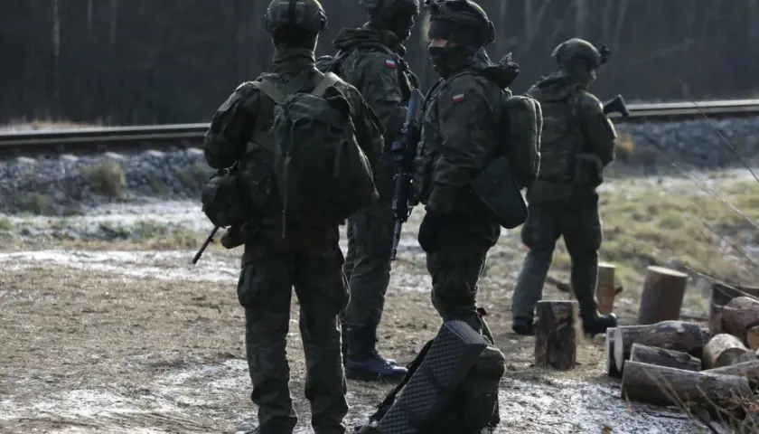 Żołnierze w kamuflażu stoją przy torach kolejowych. Ich zarobki w wojsku pozwalają na wyposażenie i szkolenia.