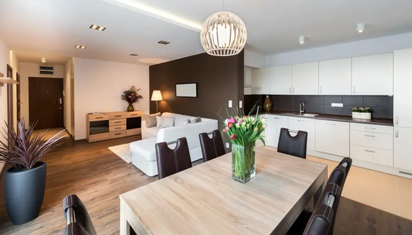 Salon moderne avec cuisine ouverte, table en bois et tulipes. Idéal pour un primo accédant cherchant un espace de vie lumineux et fonctionnel.