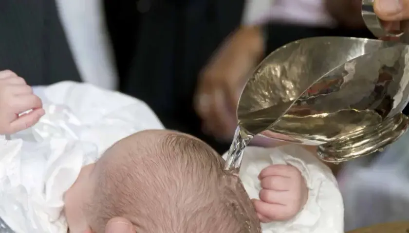 Taufe eines Babys mit Wasser aus einem silbernen Gefäß.