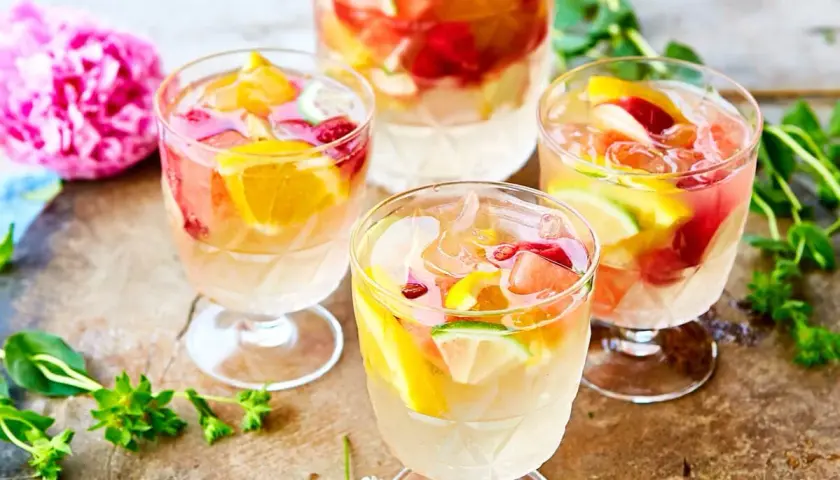 Tre glas med uppfriskande sangria vit fyllda med frukt och is. En perfekt sommardrink!