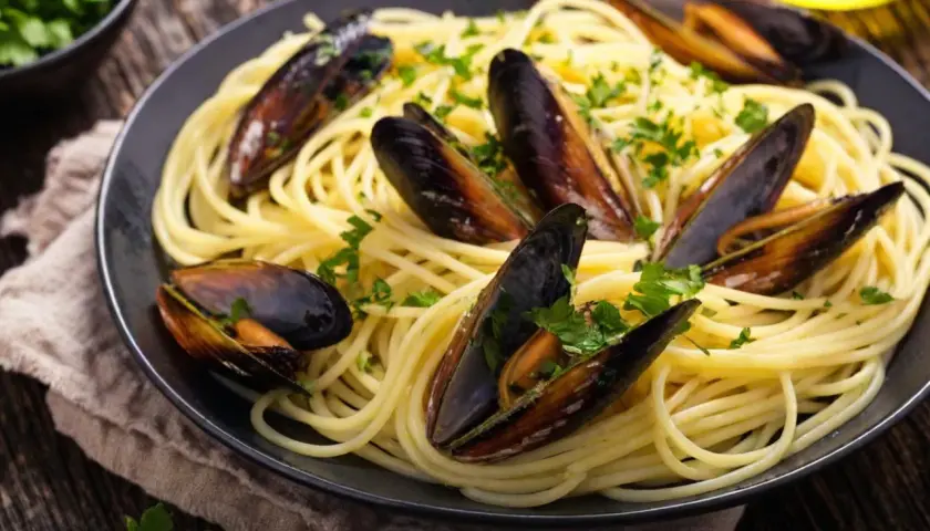Un plat de spaghetti aux moules, parsemé de persil frais. Un accompagnement parfait pour des moules savoureuses.