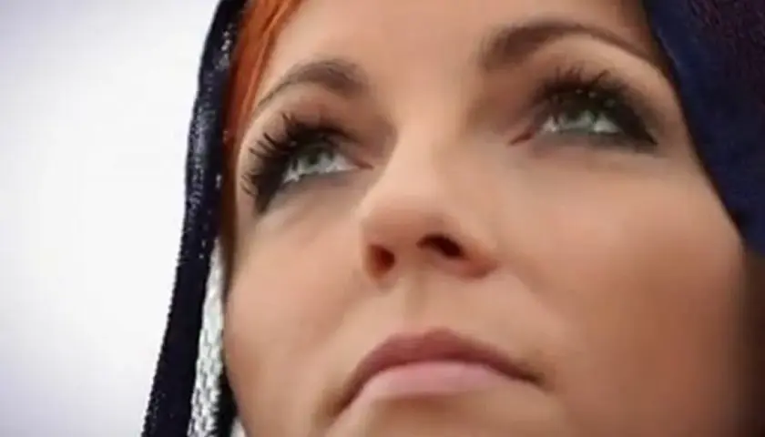 Anna Wyszkoni w zadumie, z niebieską chustą na głowie, analizuje tekst.