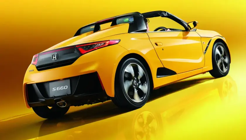 Żółta Honda S660 z otwartym dachem, widziana z tyłu, błyszczy na tle.