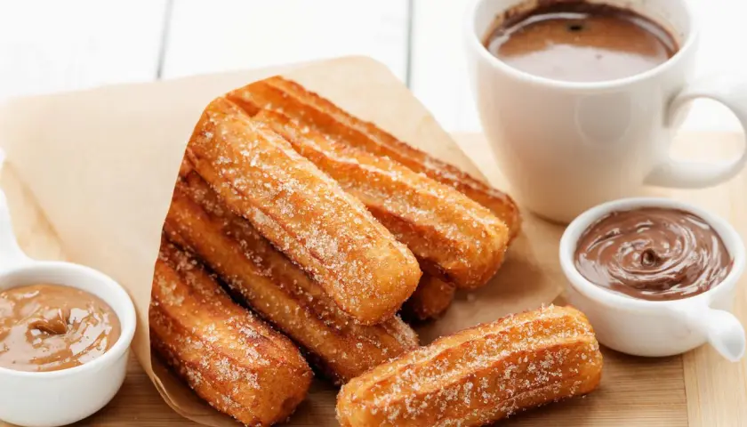 Churros dorés et croustillants, saupoudrés de sucre, prêts à être trempés dans le chocolat. Une recette gourmande pour un goûter parfait.