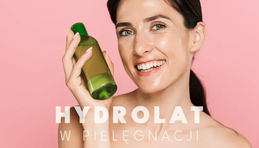 Uśmiechnięta kobieta trzyma buteleczkę z zielonym płynem. To hydrolat, który odświeża i nawilża skórę.