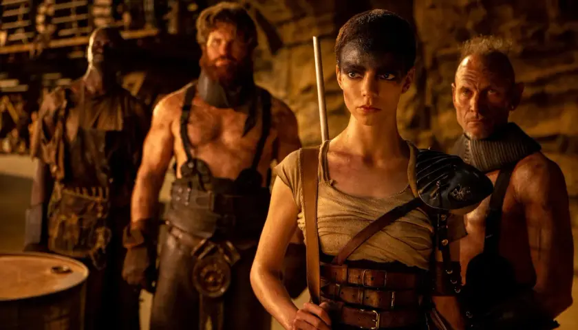 Furiosa z "Sagi Mad Max" w otoczeniu groźnych towarzyszy, gotowa do walki w postapokaliptycznym świecie.